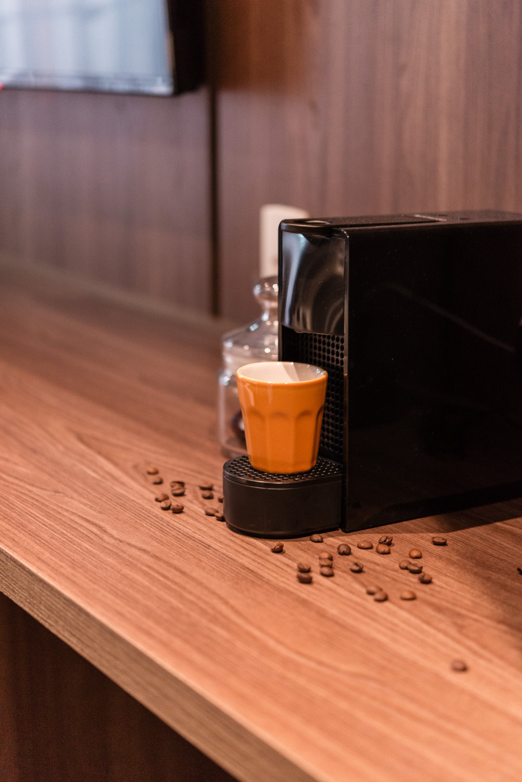 Detalhe da cafeteira sobre a bancada de madeira com xícara terracota