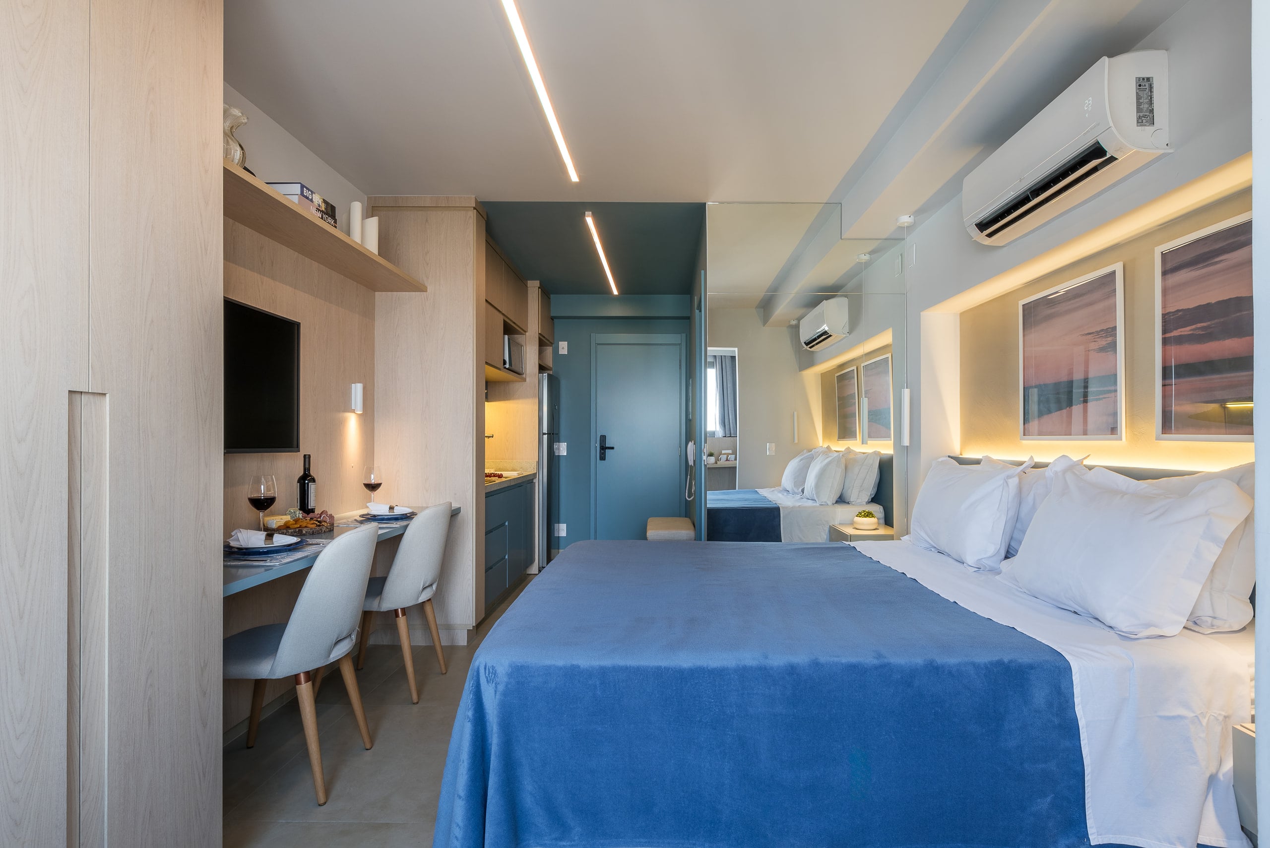 Ângulo do studio mostrando cozinha, bancada e cama em sequência