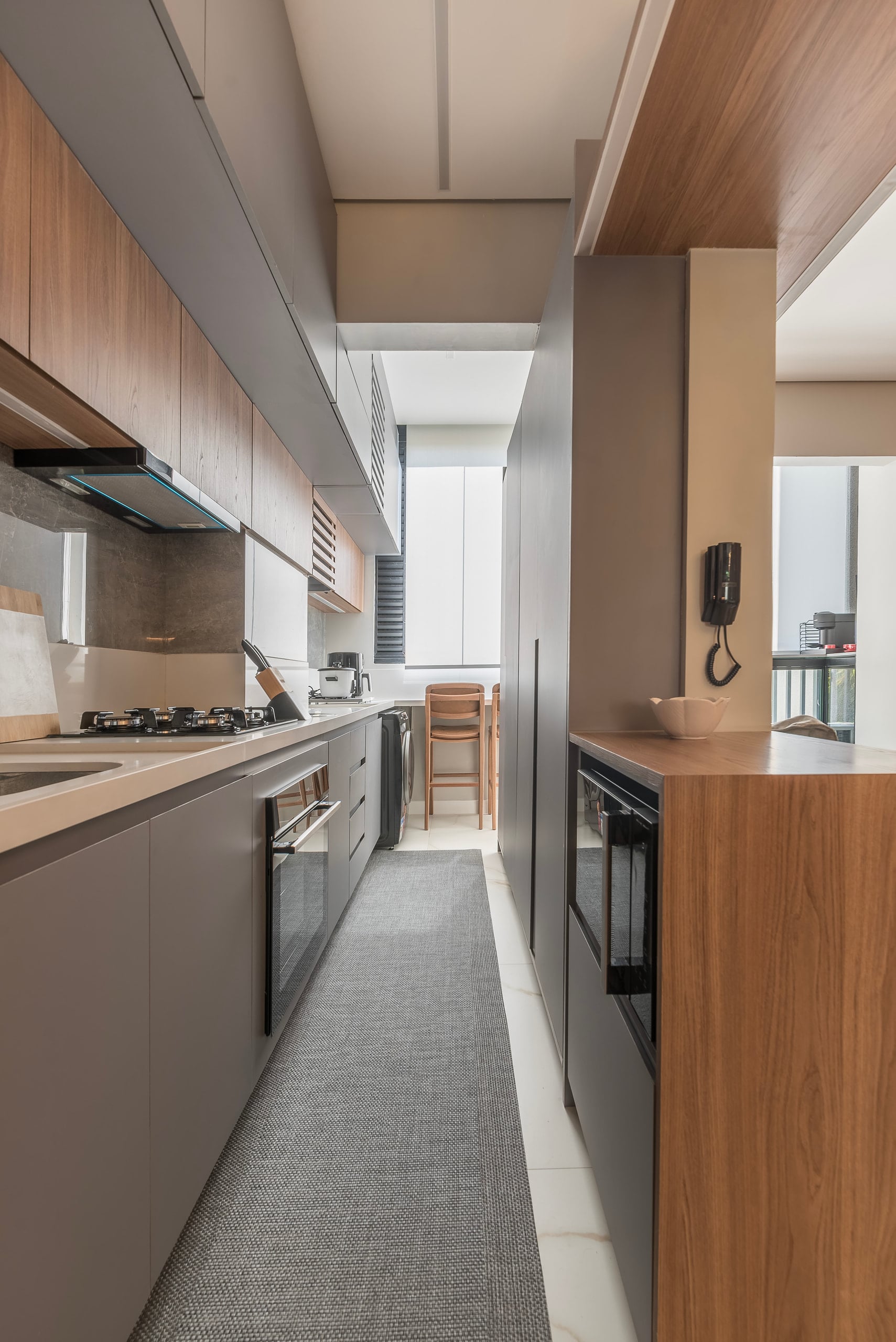 Cozinha em corredor com bancada contínua, cooktop e armários até o teto