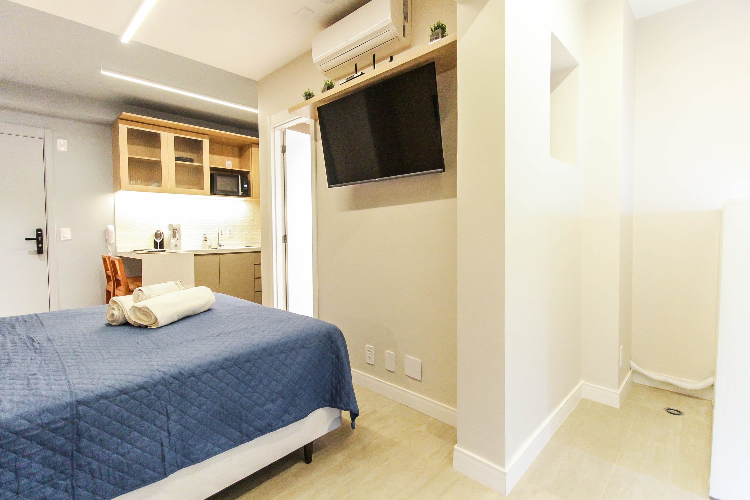 Cama de casal vista de frente, com marcenaria clara e nicho de apoio