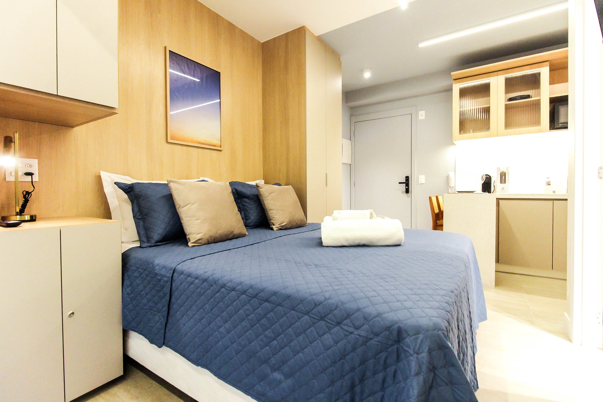 Cama com enxoval azul e a bancada da cozinha ao fundo