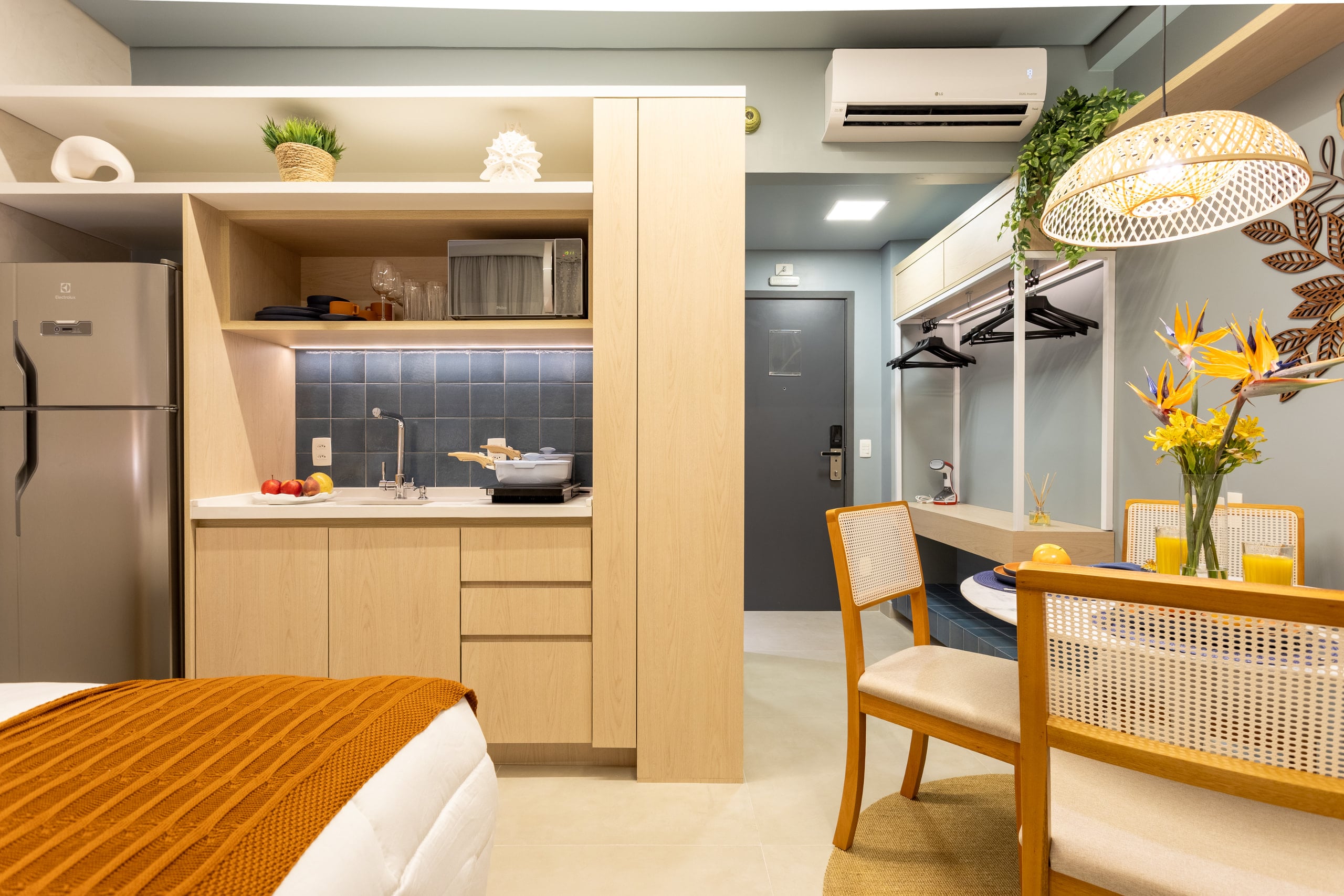 Cozinha compacta em madeira clara com cooktop, cuba e mesa de apoio