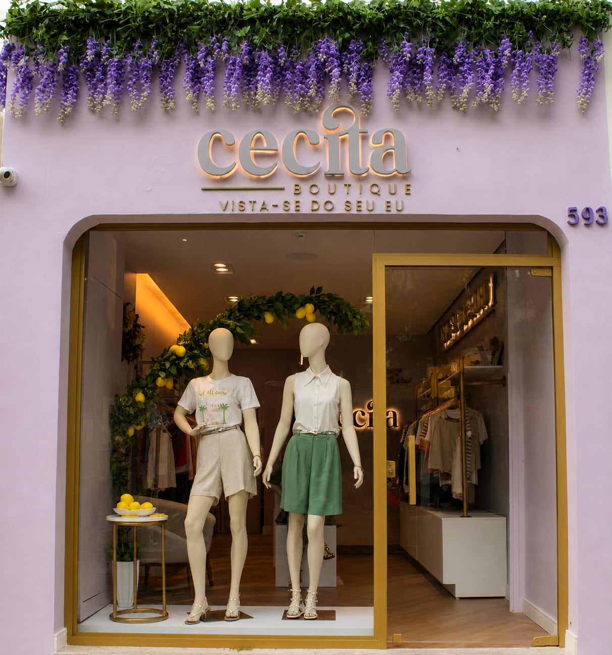 Interior da boutique com arara de roupas, manequim sentado e balcão de atendimento