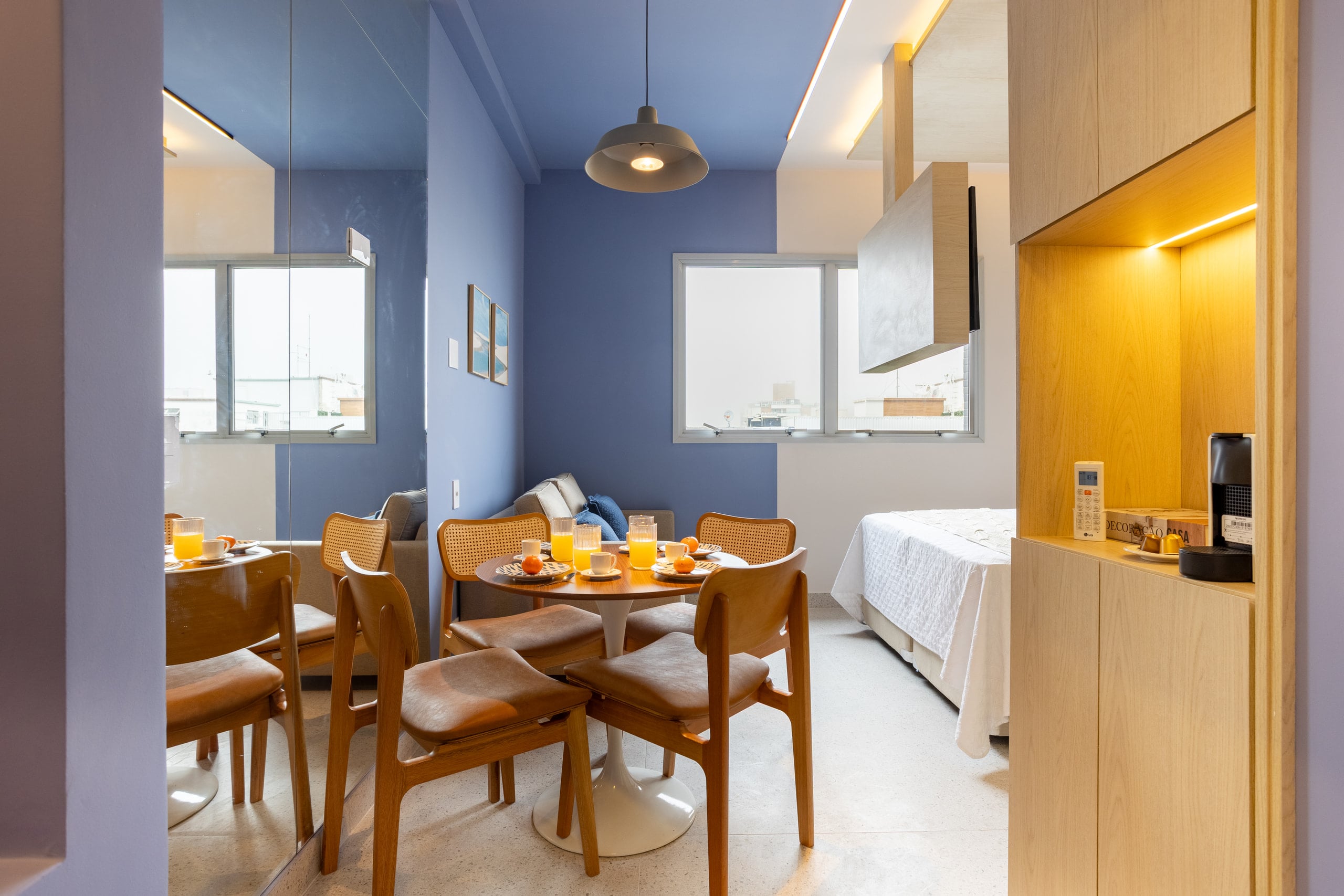 Studio com mesa de refeições, cama e paredes em azul claro